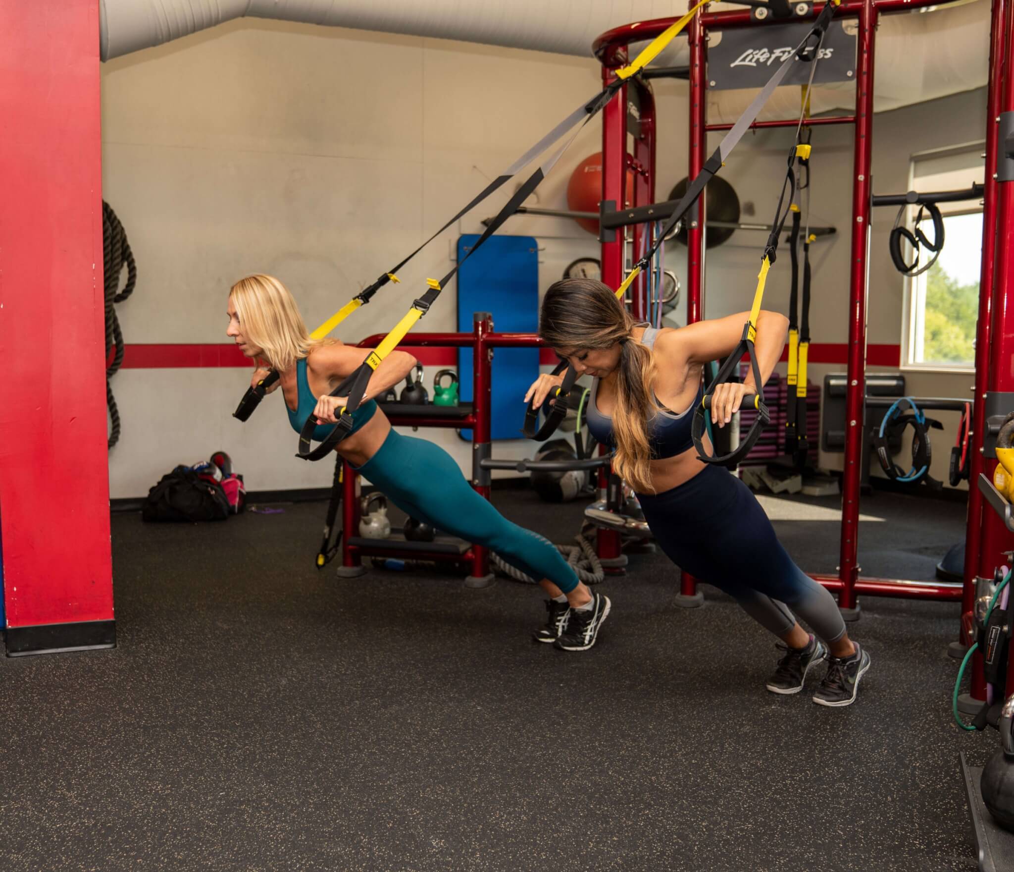 two women doing chest press on TRX