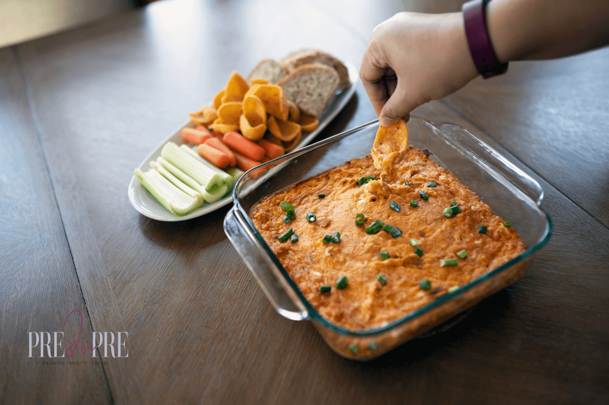 lady's hand with corn chip scoop dipping into chicken buffalo dip