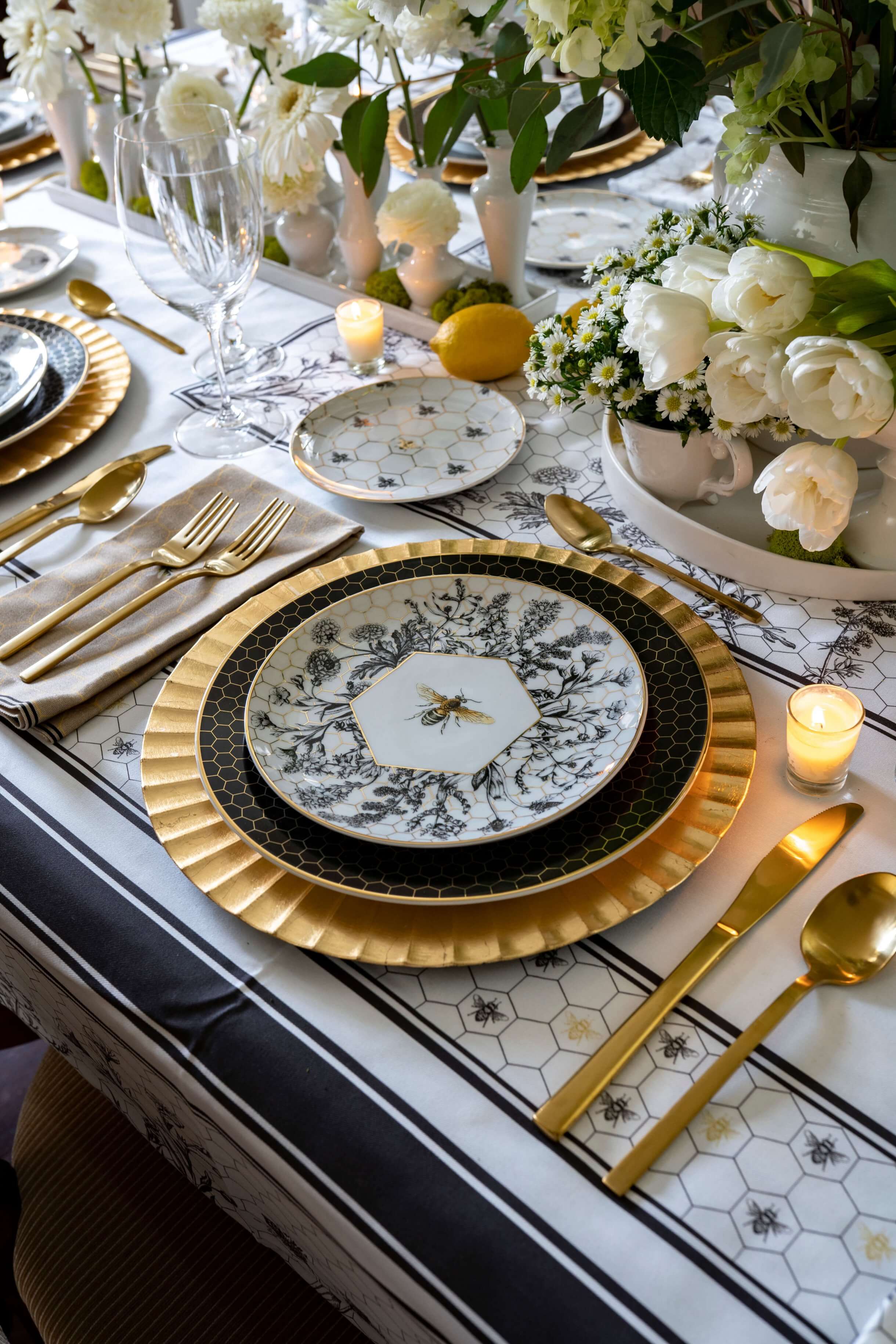 black and gold bee and floral dinnerware arranged beautifully in a formal dining room. Dinnerware set from Williams Sonoma and gold flatware from West Elm