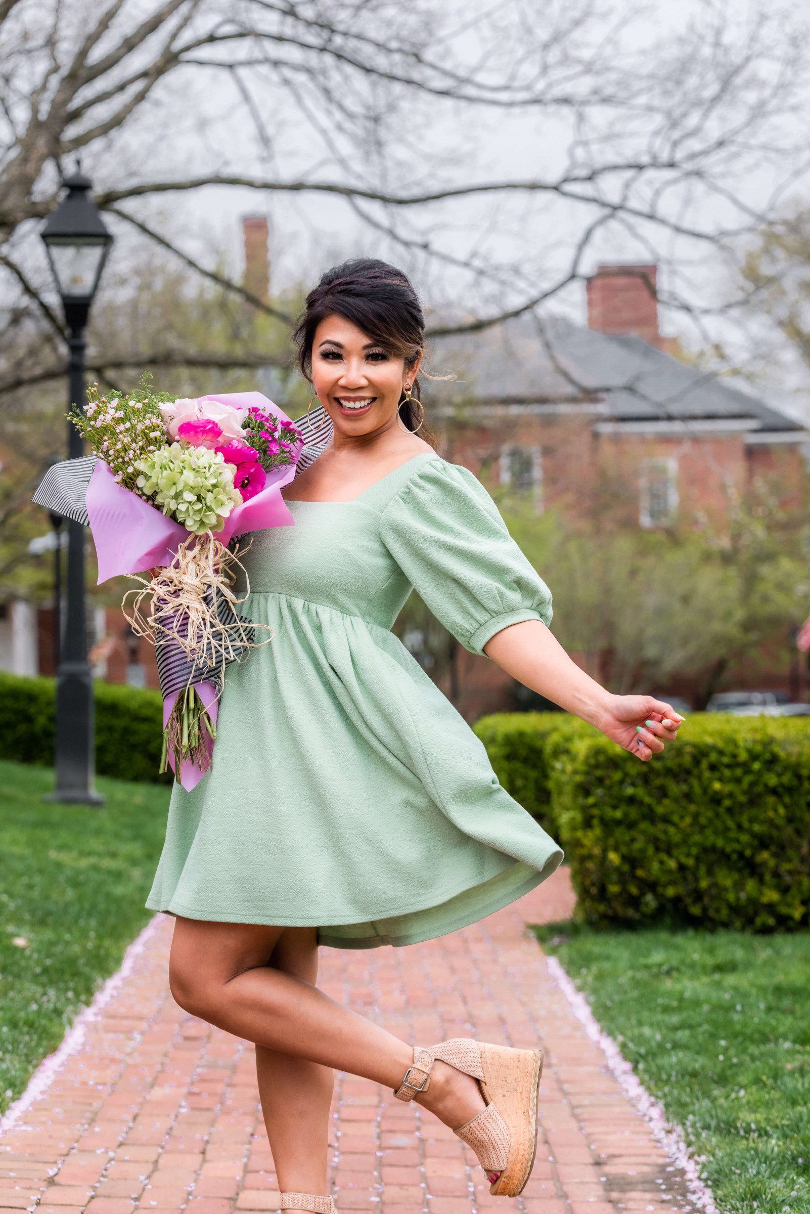 lady wearing a mint green a-line dress in cork wedge holding a mix flora bouquet.