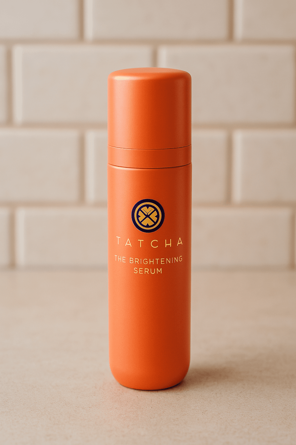 Tatcha Brightening Serum photographed at an angle against a textured beige wall and smooth stone surface. Tatcha Skincare Review